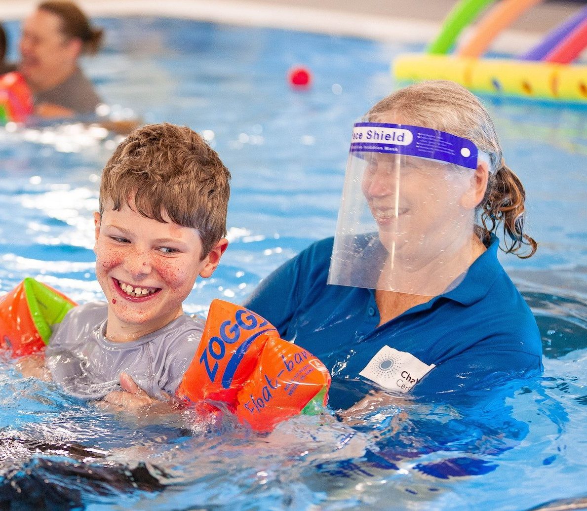 boy swimming with help from adult